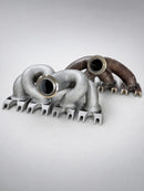 Three-quarter view of ModalWorks M177 exhaust manifold beside the OEM manifold